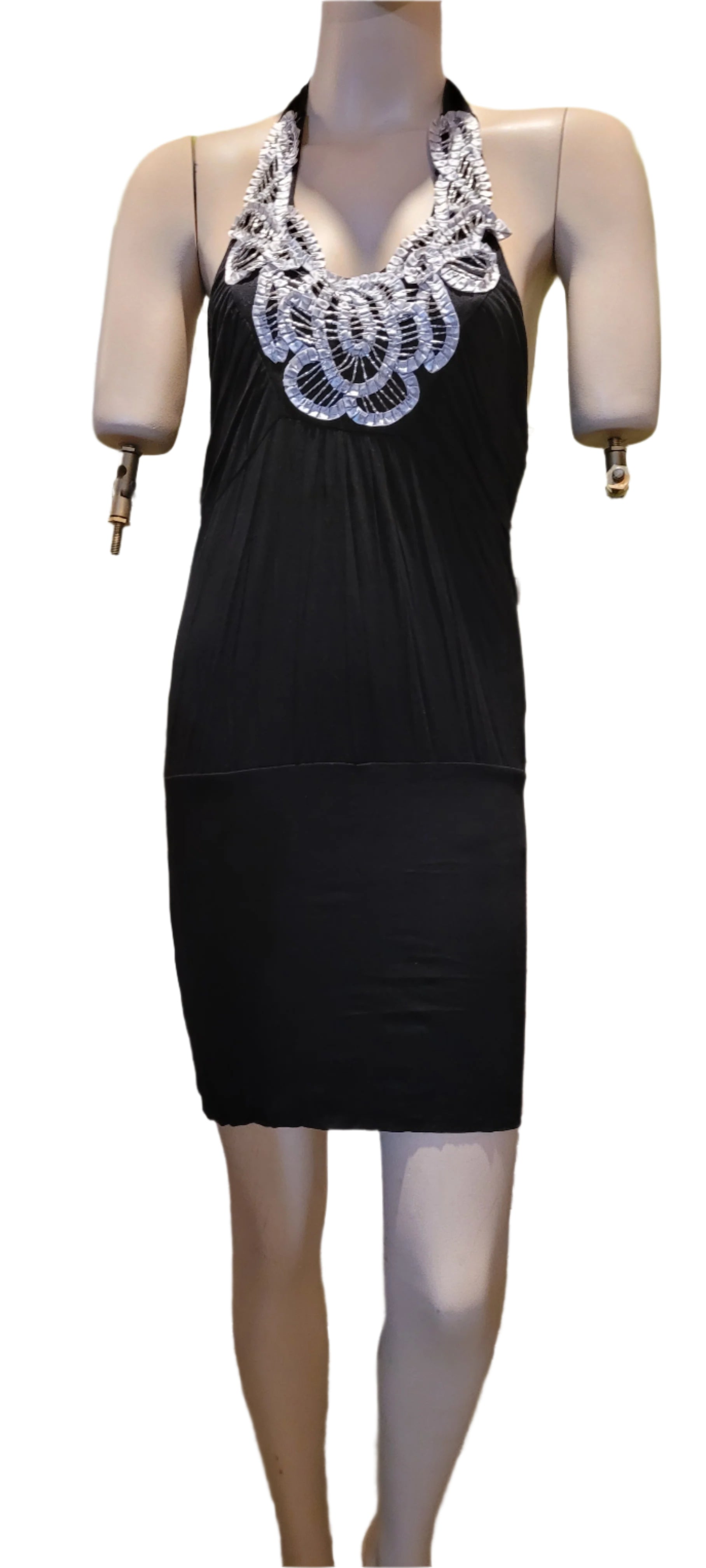 Person wearing a black dress with white lace details in front of a store window.