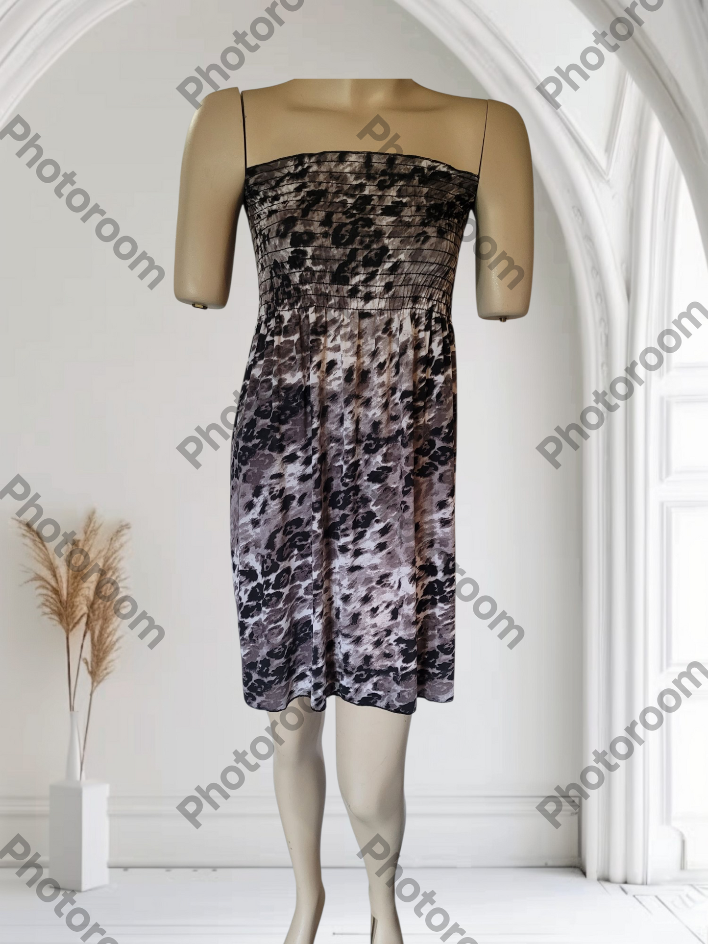 Mannequin wearing a patterned dress in a white room with 'Photoroom' watermark.