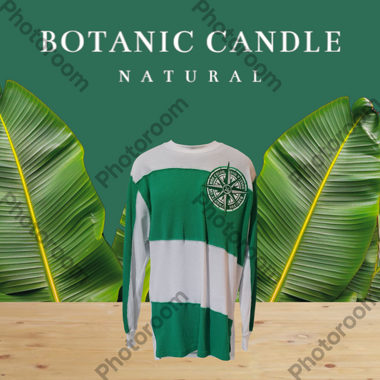 BARE FOX BRAND Green and white long-sleeve shirt with a compass design on a wooden surface with green leaves in the background, labeled 'Botanic Candle Natural'.