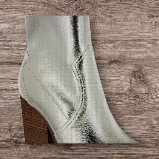 Silver metallic ankle boot with a brown block heel on a wooden surface