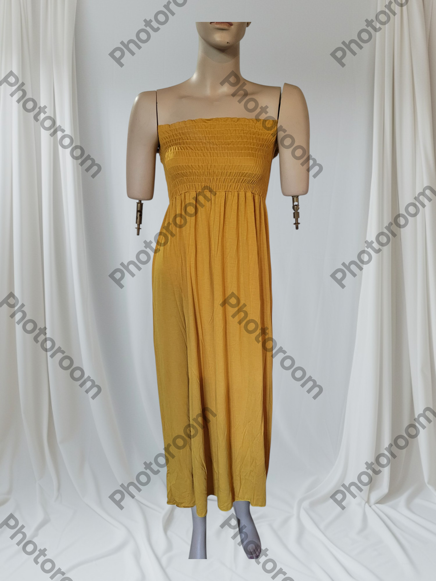 Mustard yellow strapless dress on a mannequin against a white curtain background