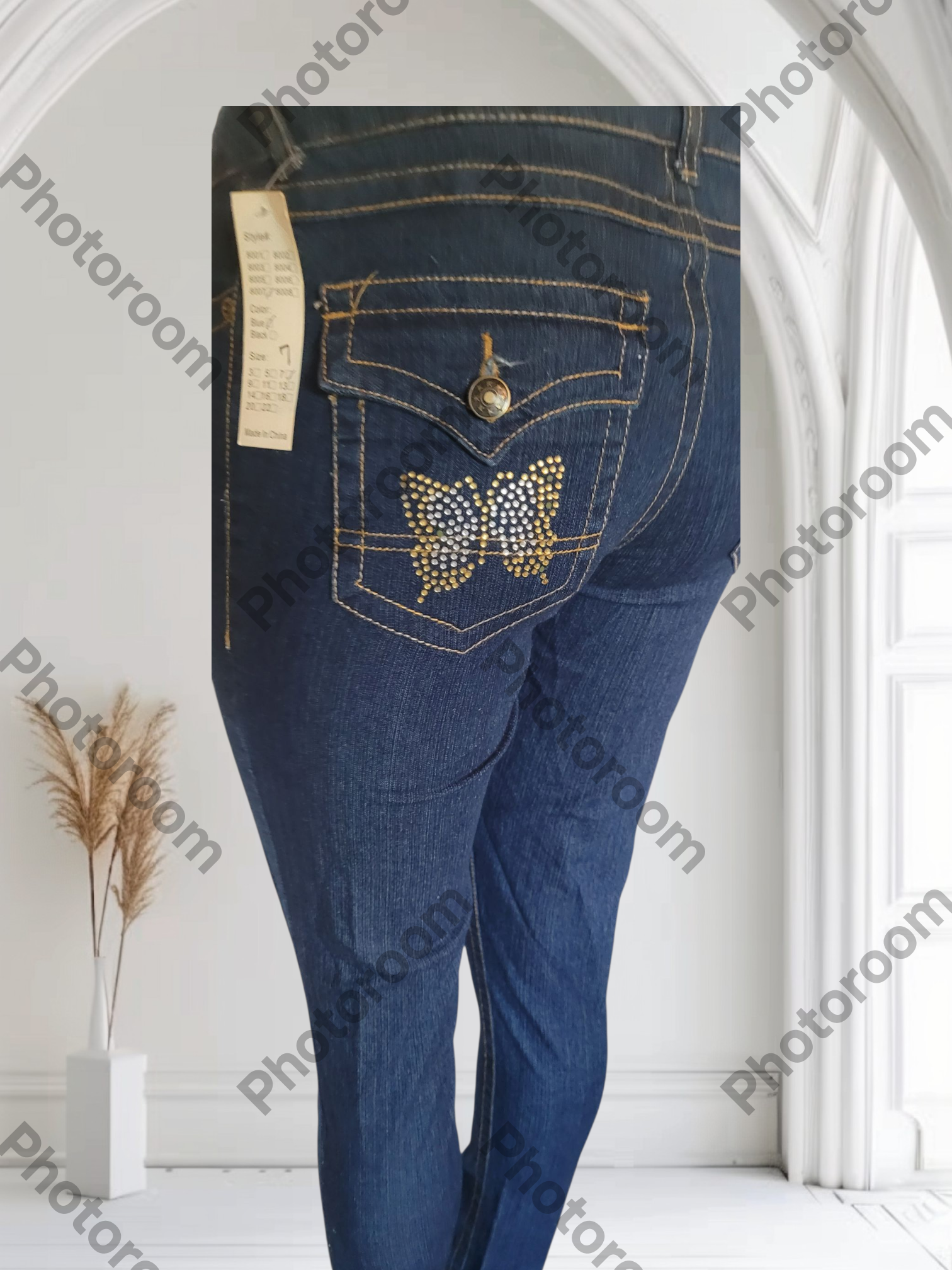 Blue jeans with a butterfly design on the pocket against a white background