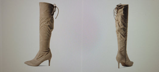 Pair of beige knee-high boots on a light gray background